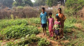 Anna with her children in her nutrition garden getting vegetables 9 months in a year