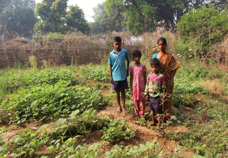 Anna with her children in her nutrition garden getting vegetables 9 months in a year